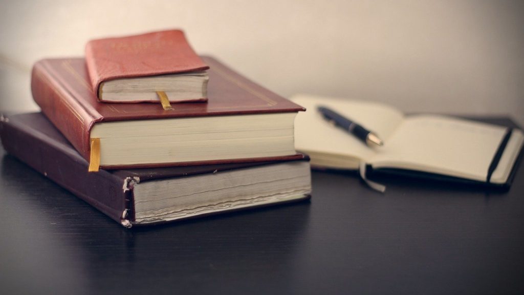 Three books, a pen and a small notebook