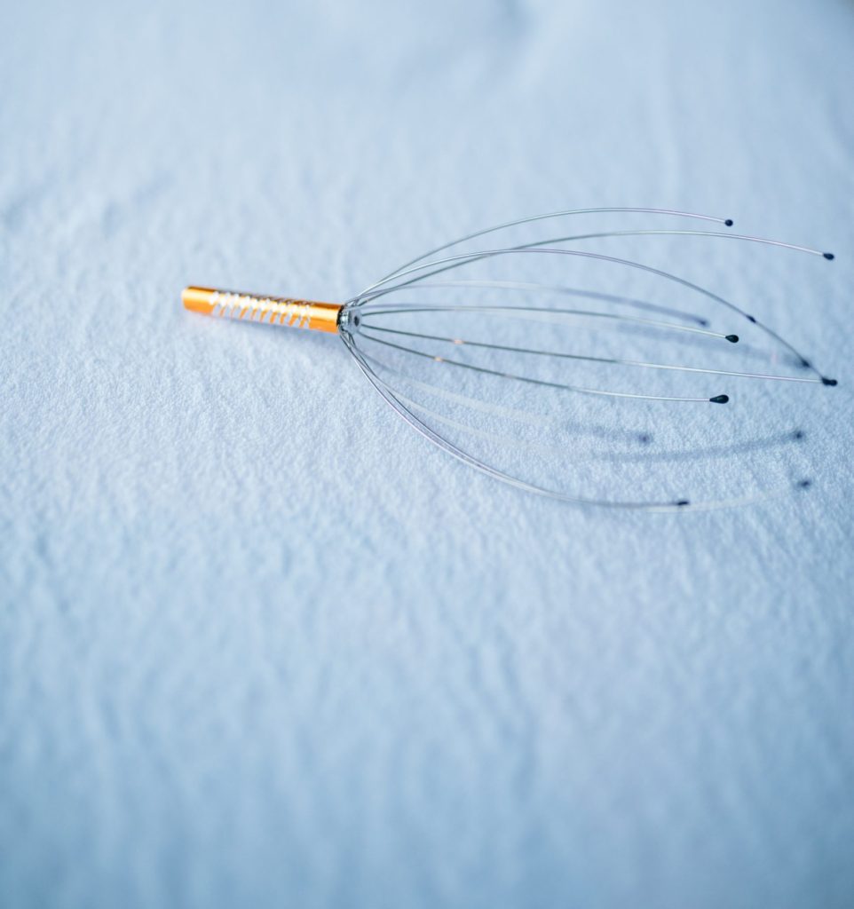 Head massager on top of white sheet